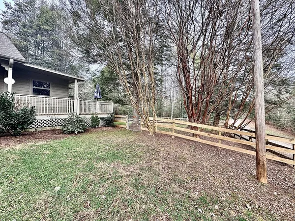 a view of backyard with wooden fence and large trees