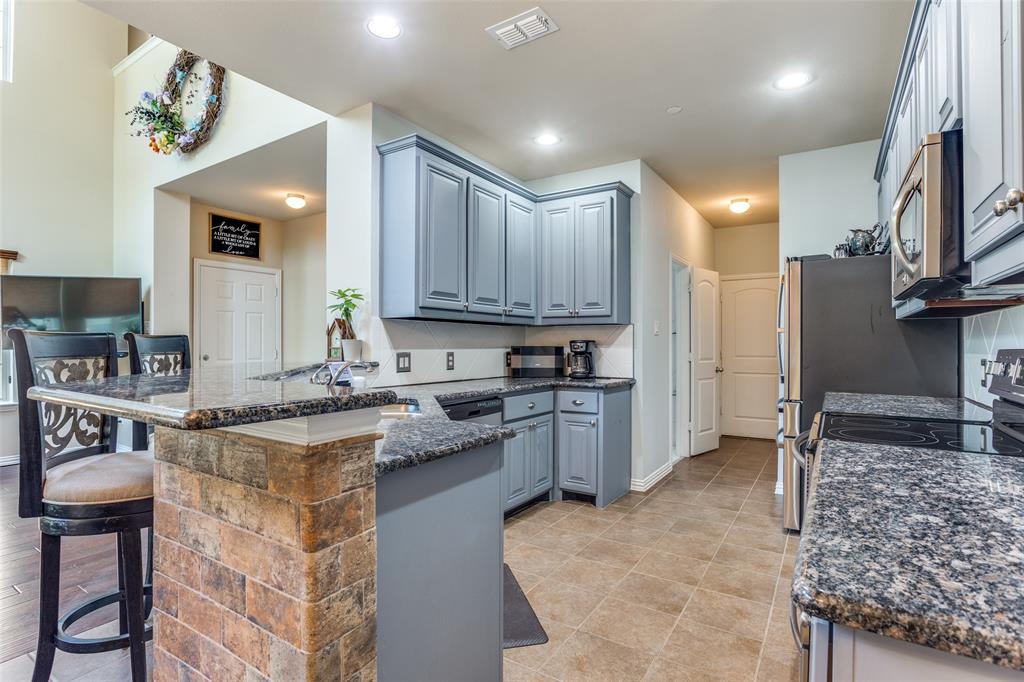 a kitchen with kitchen island granite countertop a stove sink cabinets and refrigerator
