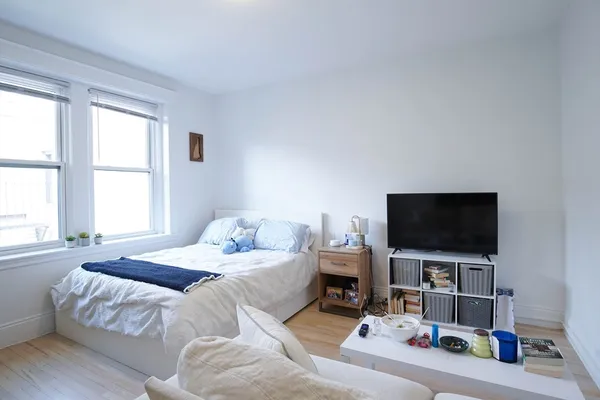 a bedroom with a bed and a flat tv screen on a dresser