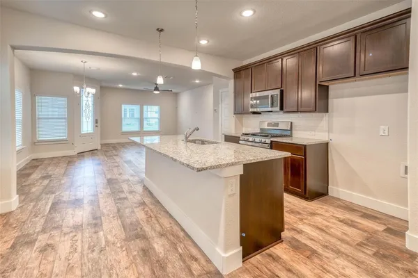 a large kitchen with stainless steel appliances kitchen island granite countertop a large counter top and wooden cabinets