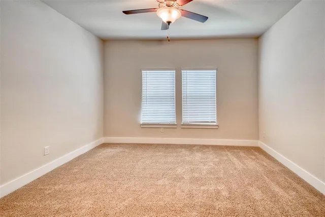 an empty room with a window and a ceiling fan