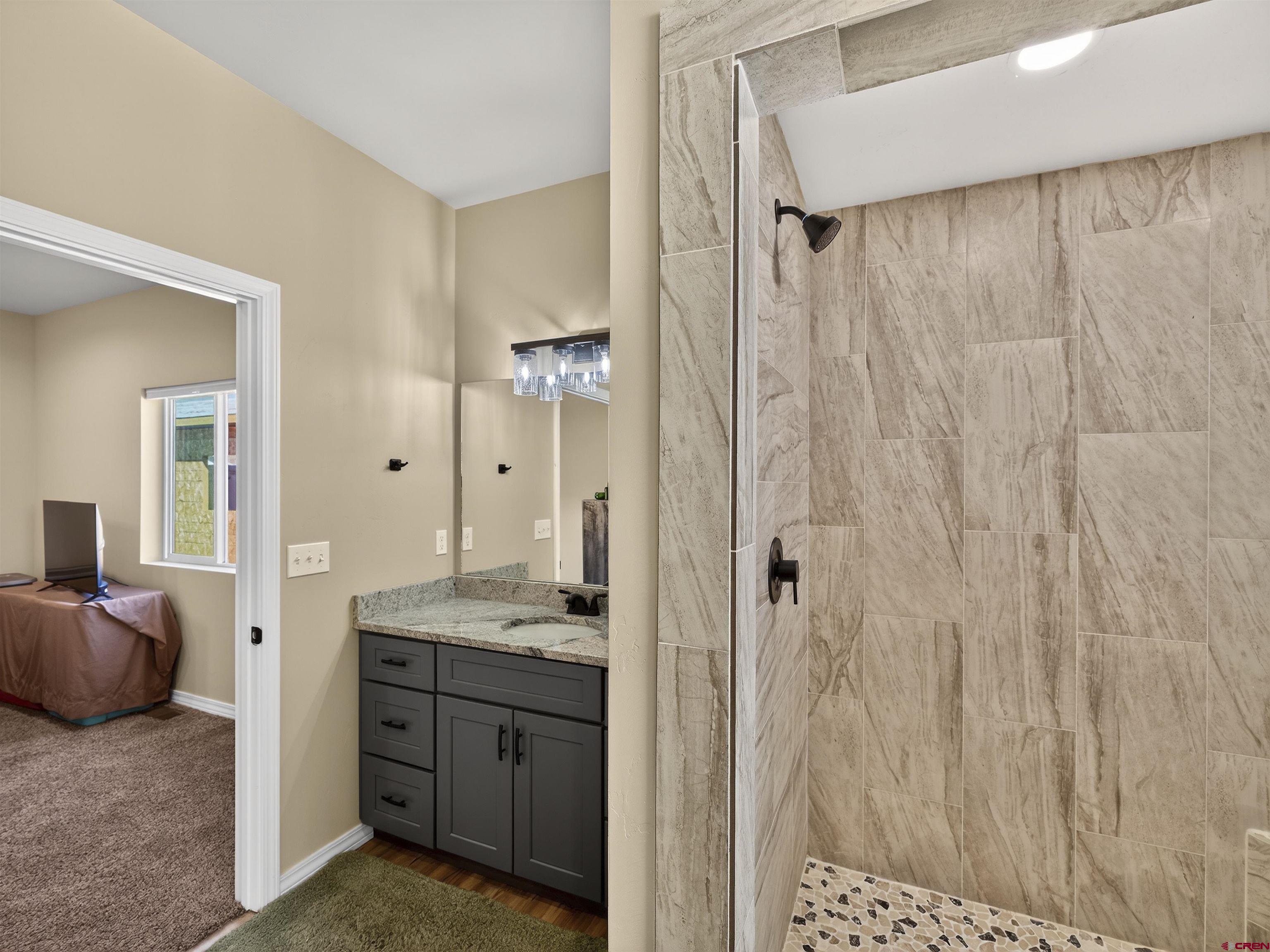 1615 Rivera Street Cortez, CO 81321 - Photo 10 of 21 a bathroom with a granite countertop sink a mirror and a shower