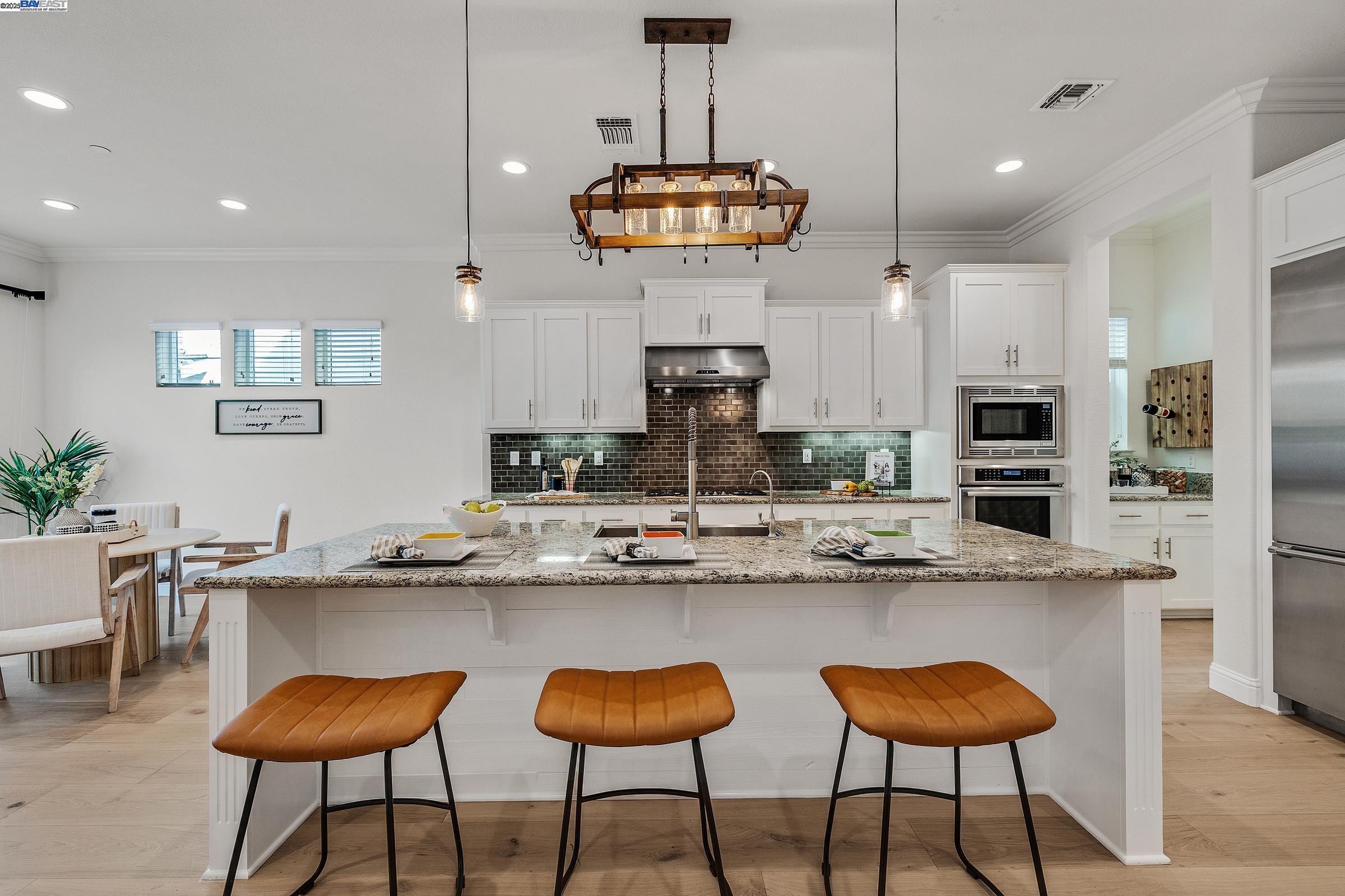 4519 Spring Mountain Way Dublin, CA 94568 - Photo 11 of 52 a kitchen with stainless steel appliances kitchen island a large island and chairs in it