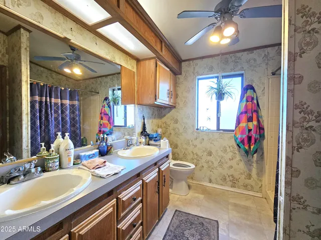 a bathroom with a granite countertop double vanity sink a mirror and a shower