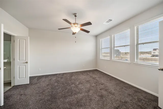 an empty room with windows and fan