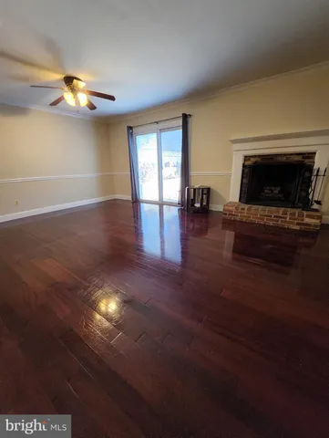 a view of empty room with fireplace and wooden floor