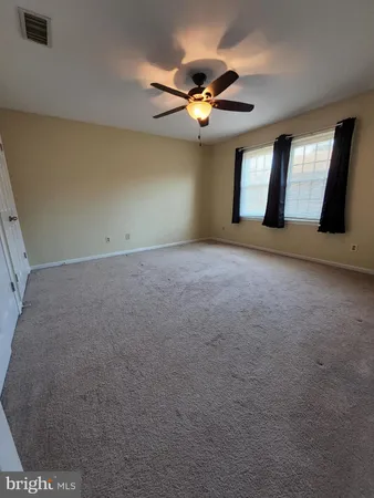a view of an empty room with chandelier fan and fire place