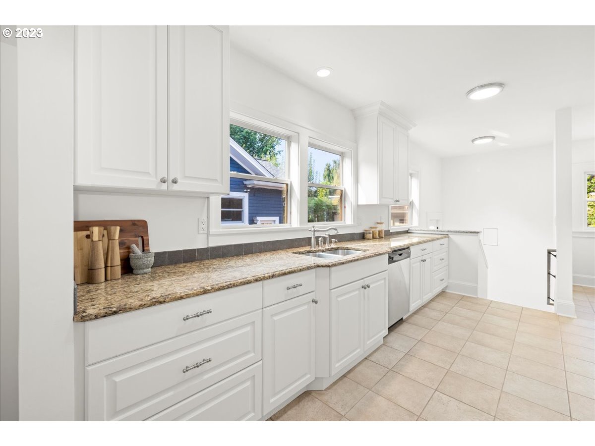 2015 Northeast 38th Avenue Portland, OR 97212 - Photo 14 of 32 a kitchen with granite countertop white cabinets white appliances a sink and a window