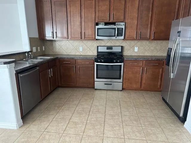a kitchen with stainless steel appliances granite countertop a stove a refrigerator and a microwave