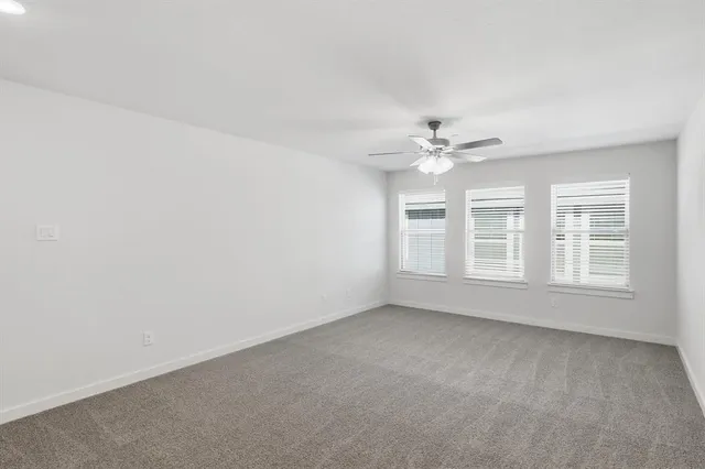 an empty room with a ceiling fan and window