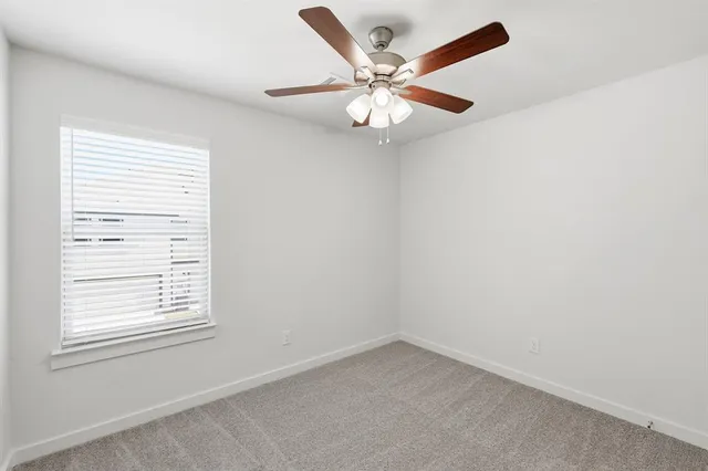 an empty room with a window and a fan
