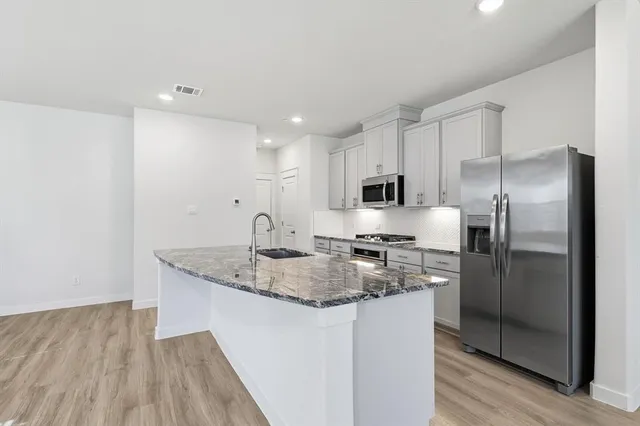 a kitchen with stainless steel appliances granite countertop a refrigerator a sink a stove a microwave and island