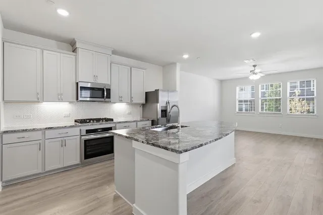 a kitchen with stainless steel appliances granite countertop a stove a sink and a microwave