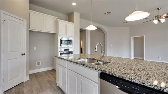 a kitchen with stainless steel appliances granite countertop a stove a sink and a white cabinets
