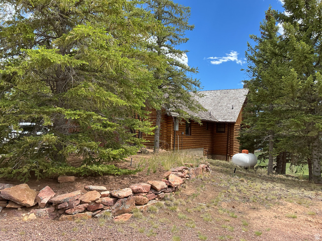 550 State Line Road Manila, UT 84046 - Photo 38 of 41 Log cabin exterior with a cedar shake roof, surrounded by mature pine trees