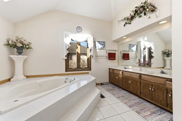 a spacious bathroom with a tub sink and mirror