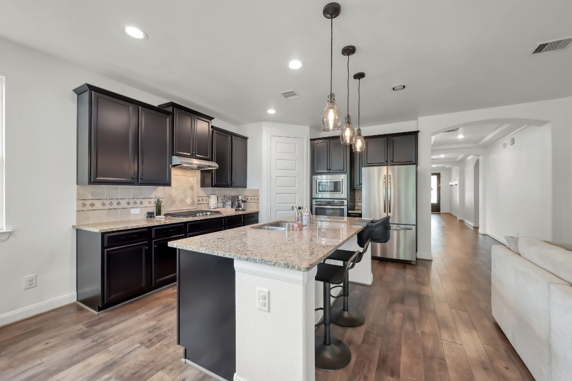 22202 Weller Oaks Drive Spring, TX 77389 - Photo 11 of 39 a large kitchen with a center island wooden floor stainless steel appliances and cabinets