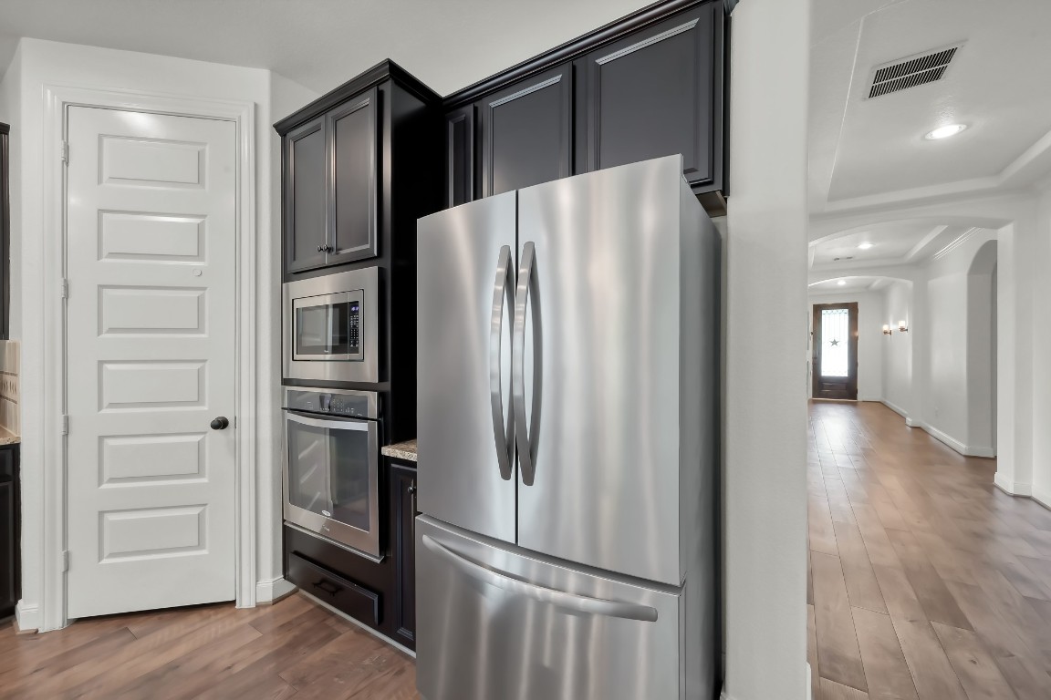 22202 Weller Oaks Drive Spring, TX 77389 - Photo 8 of 39 a view of a refrigerator in kitchen and an empty room with wooden floor