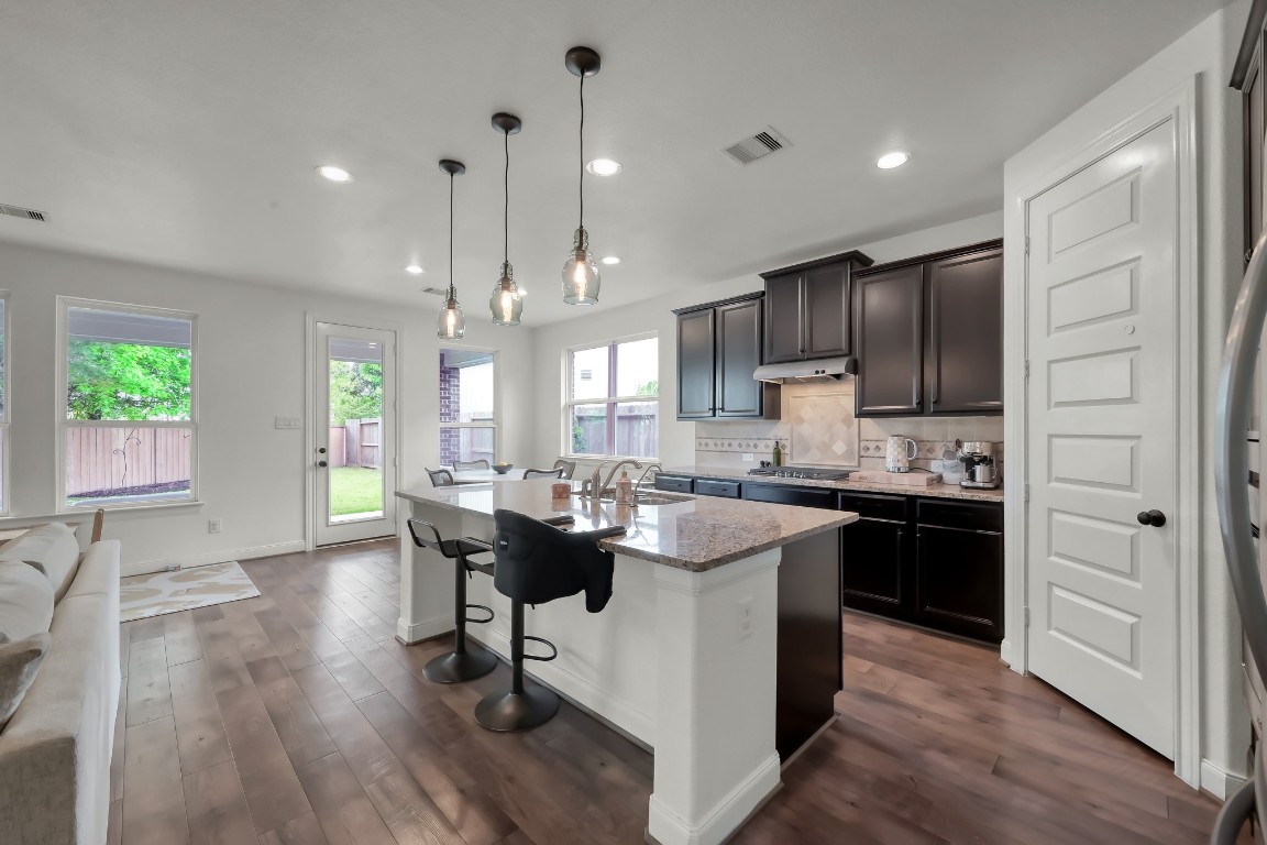 22202 Weller Oaks Drive Spring, TX 77389 - Photo 9 of 39 a kitchen with kitchen island granite countertop a sink cabinets and wooden floor