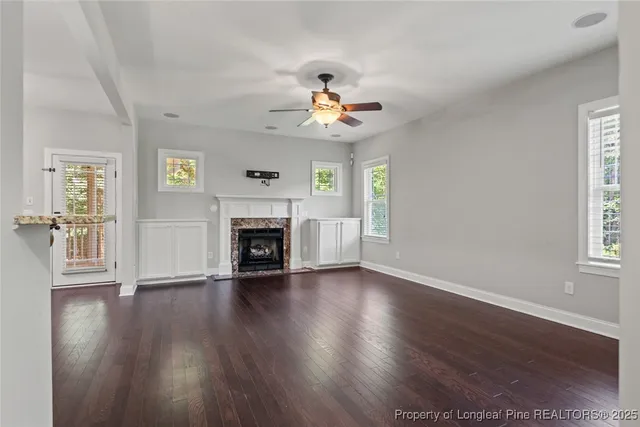 an empty room with wooden floor fireplace and windows