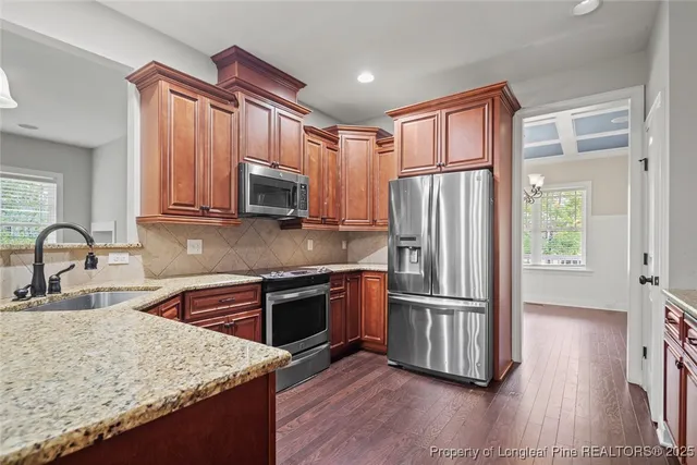 a kitchen with granite countertop a refrigerator stove top oven and sink