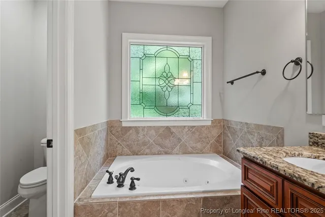 a bathroom with a granite countertop bathtub and a toilet
