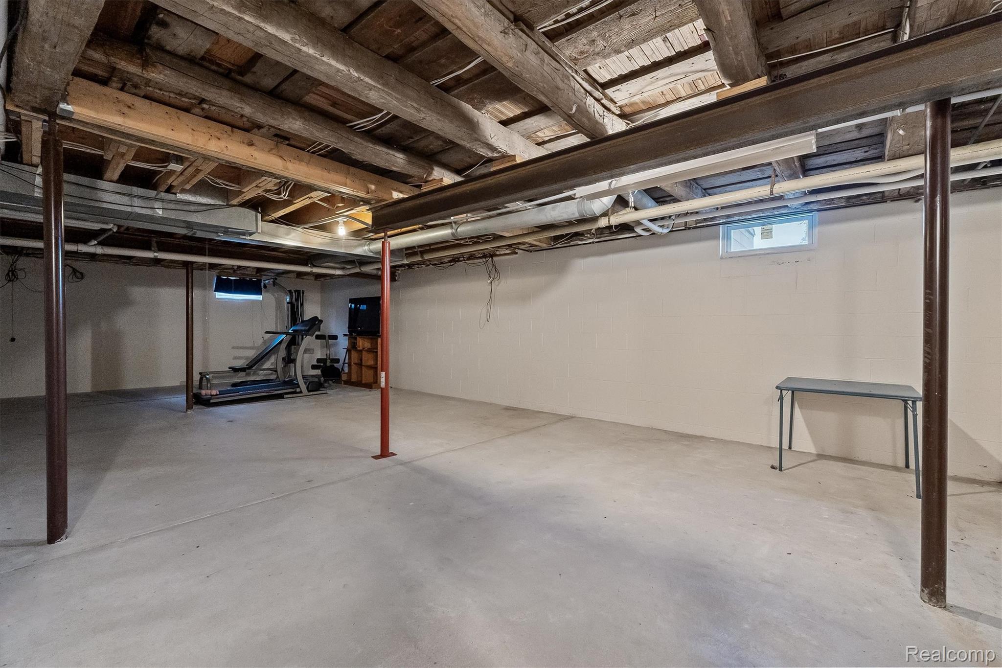 3553 North State Road Owosso, MI 48867 - Photo 29 of 45 Unfinished basement with exposed ceiling beams, concrete flooring, and an egress window