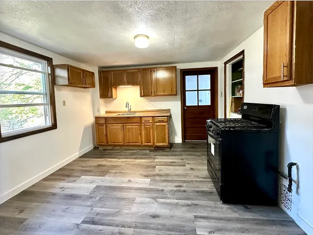a view of a kitchen with kitchen island granite countertop stainless steel appliances stove sink and cabinets