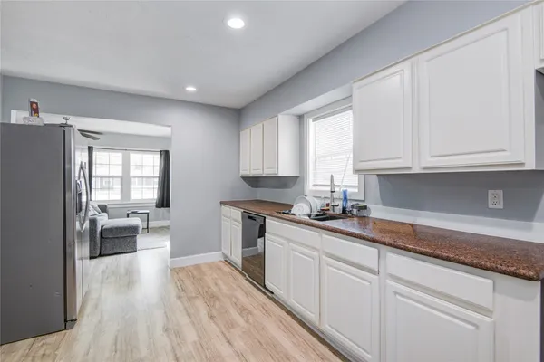 a kitchen with white cabinets and wooden floor