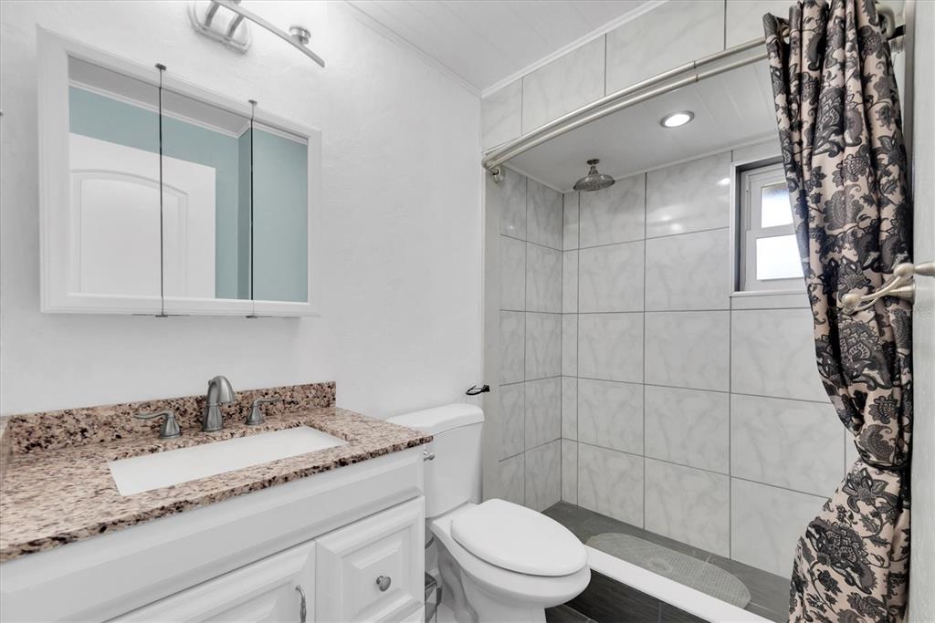 10032 65th Avenue North, Unit 24 St. Petersburg, FL 33708 - Photo 21 of 56 a bathroom with a granite countertop sink a toilet and shower