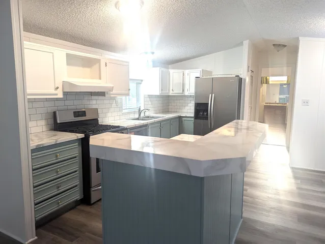 a kitchen with stainless steel appliances granite countertop a sink stove and refrigerator
