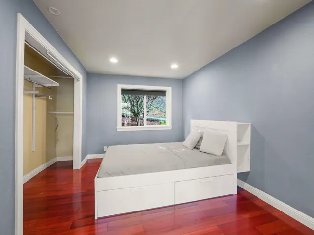 a bedroom with a large bed and a wooden floor