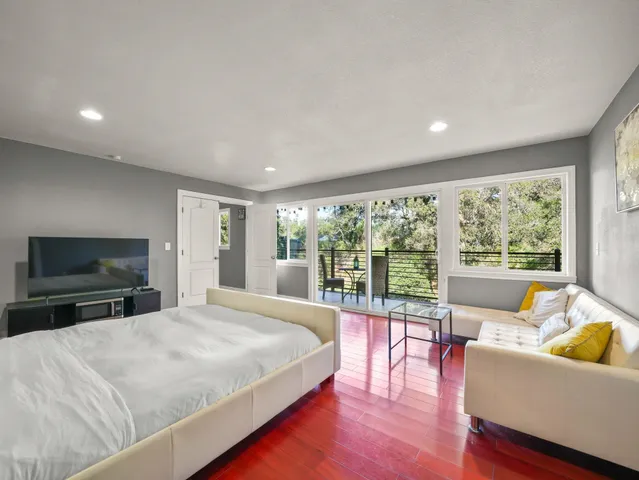 a large bedroom with a large window and a flat screen tv