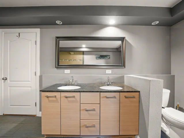 a bathroom with a granite countertop sink and a toilet