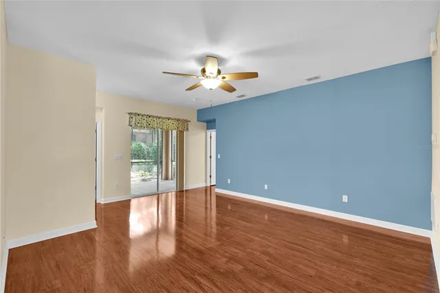 a view of an empty room with window and wooden floor
