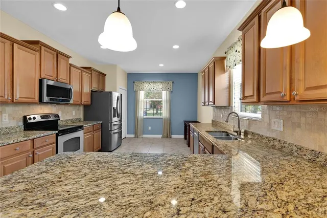 a kitchen with granite countertop a stove sink microwave and refrigerator