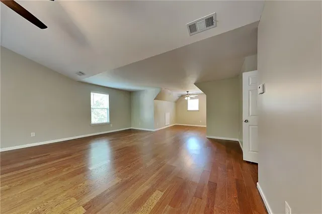 a view of an empty room with wooden floor and window