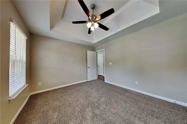 an empty room with ceiling fan and window