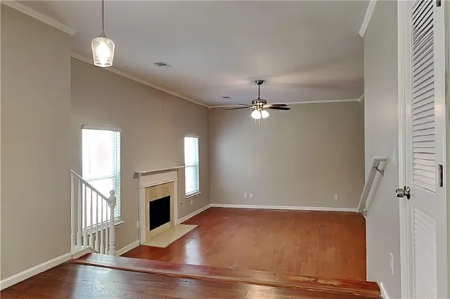 an empty room with wooden floor fireplace and windows