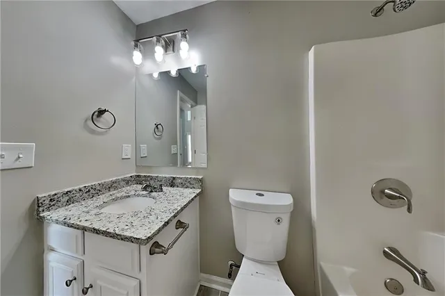 a bathroom with a granite countertop sink a toilet and a mirror