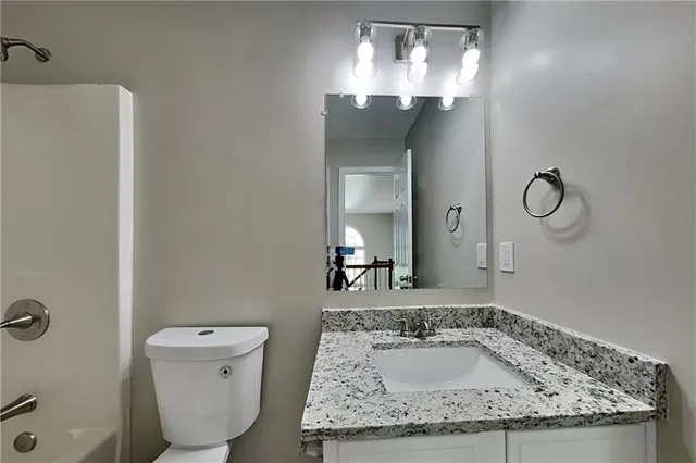 a bathroom with a granite countertop sink a toilet and mirror