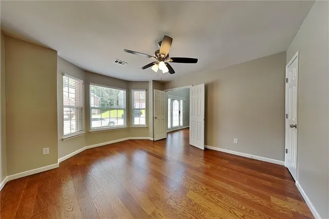 a view of an empty room with a window and wooden floor