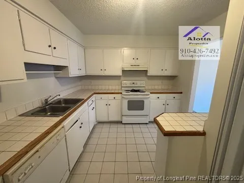 a kitchen with a sink a stove top oven and cabinets