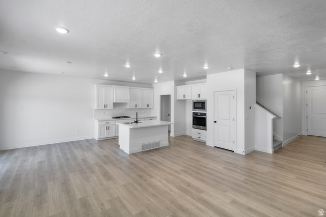 2840 West Aurora Avenue Mapleton, UT 84664 - Photo 4 of 14 Open-concept main level featuring wood-finish flooring, recessed lighting, and a white kitchen with shaker cabinetry