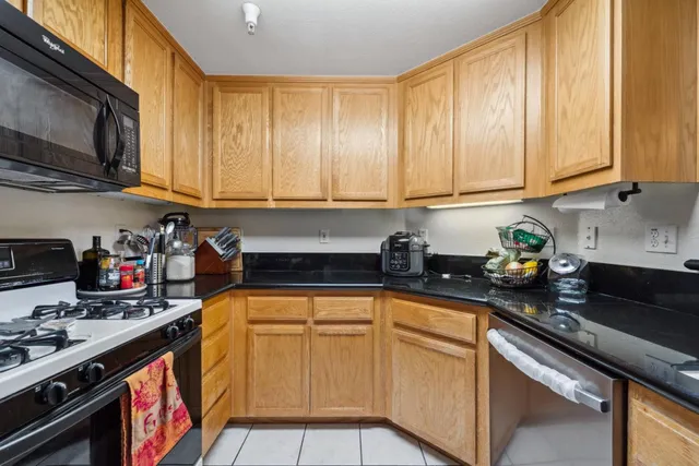 a kitchen with stainless steel appliances granite countertop a stove a sink dishwasher and cabinets with wooden floor
