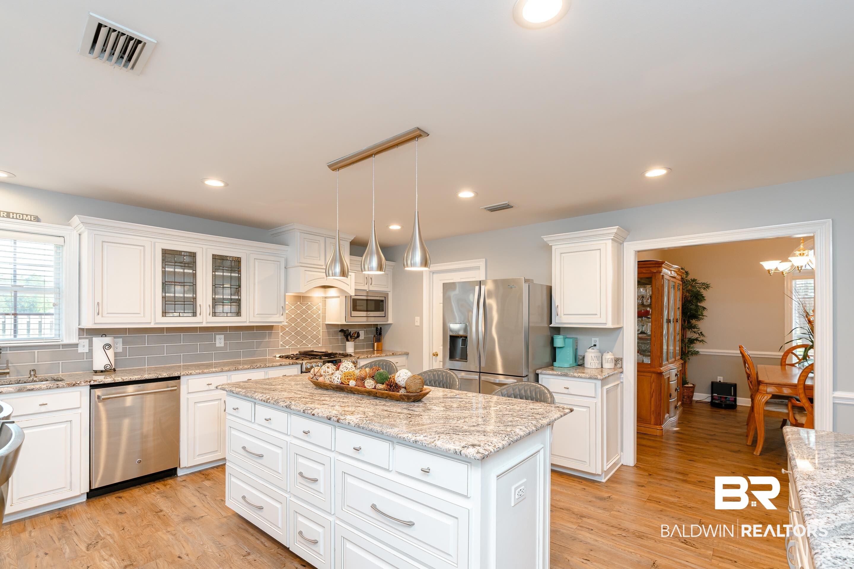 9477 Deerfield Drive Irvington, AL 36544 - Photo 14 of 58 Kitchen with stainless steel appliances, light hardwood / wood-style floors, white cabinetry, and a center island