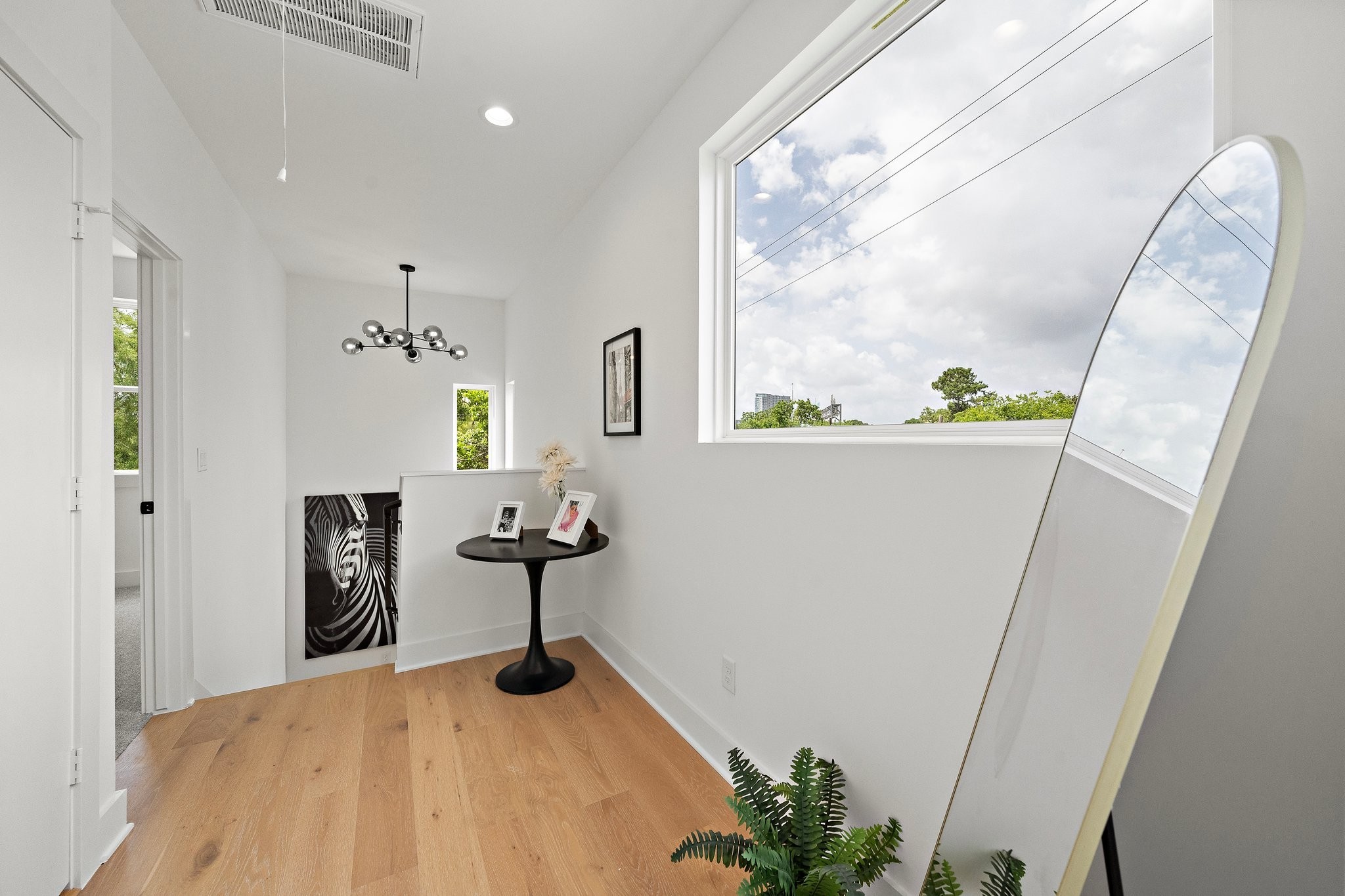 1607 Barbee Street Houston, TX 77004 - Photo 16 of 27 The third-floor hallway offers a statement chandelier suspended above the staircase, creating a stunning focal point. Natural light pours in through nearby windows, highlighting the open layout and elegant finishes that connect the upper level with effortless style.