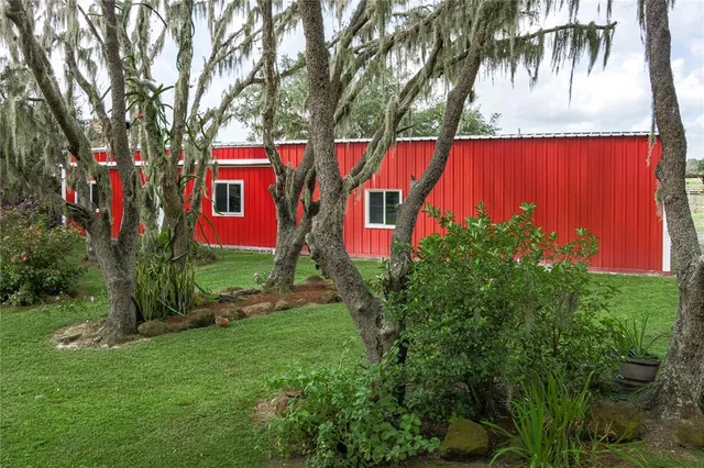 a kitchen with stainless steel appliances kitchen island granite countertop a refrigerator a stove top oven a dining table and chairs with wooden floor