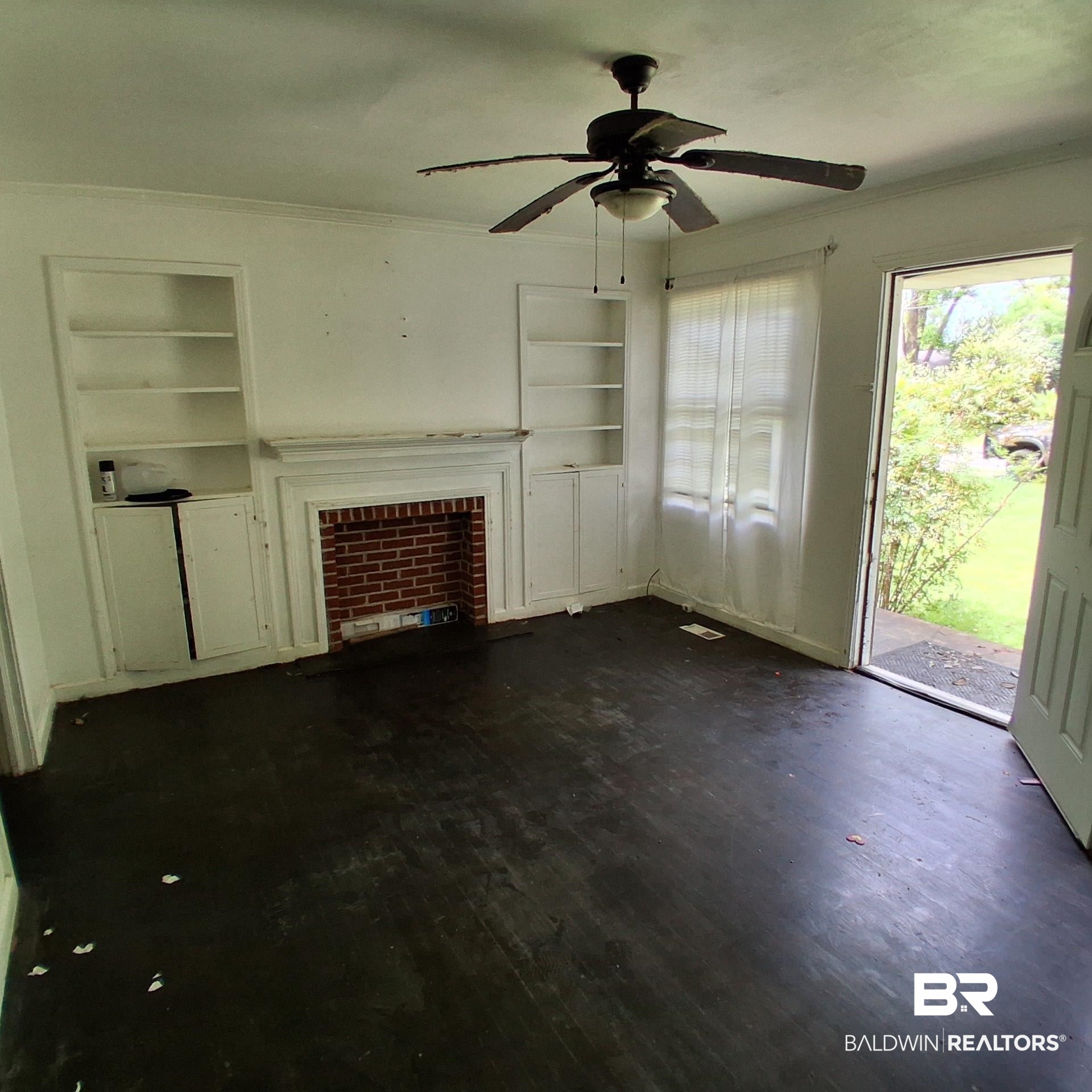 403 Bruner Avenue Evergreen, AL 36401 - Photo 5 of 9 Living space featuring wood-finish flooring, a brick fireplace with a white mantel, and built-in shelving with cabinetry