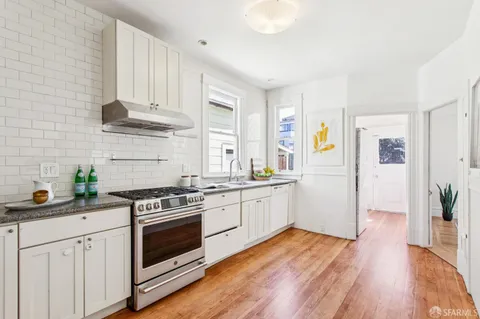 a kitchen with a white cabinets a sink dishwasher and a stove with wooden floor